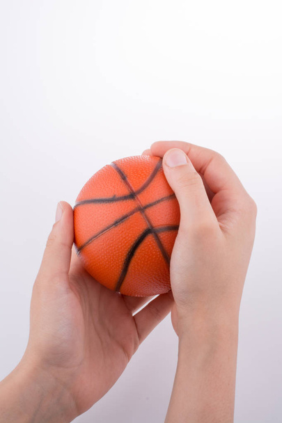 Hand holding an orange basketball model on a white background - Foto, afbeelding