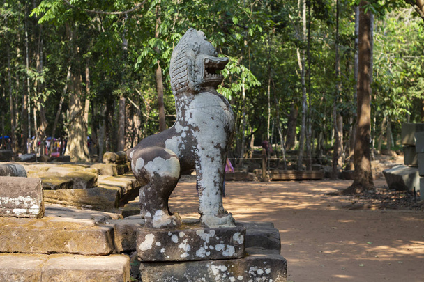 Mossy stone lion statue, Angkor Wat temple complex, Cambodia. Spiritual protector Barong. Ancient temple in Siem Reap. Angkor Wat landscape. Travel and sightseeing in Asia. Tourist place of interest. - Foto, afbeelding