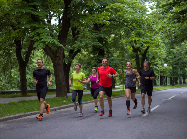 группа здоровых людей бег трусцой в городском парке, команда бегунов на утренней тренировке - Фото, изображение