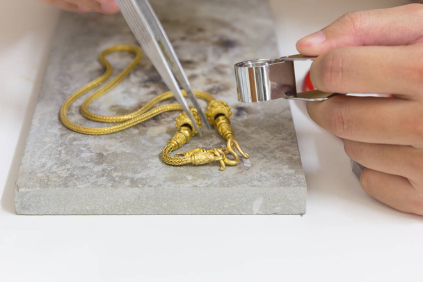 Arany nyaklánc kézzel kézműves-háttér fehér asztal kő. - Fotó, kép