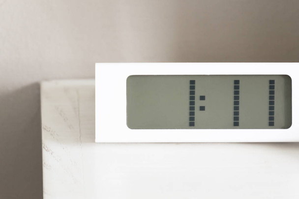 De digitale moderne witte klok op witte tafel in slaapkamer. - Foto, afbeelding