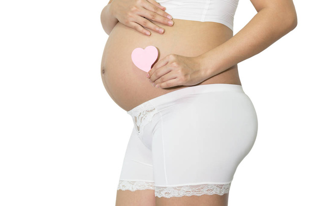 Pregnant woman hand holding blank pink paper note heart on belly, healthy concept, with copy space isolated white background. - Valokuva, kuva