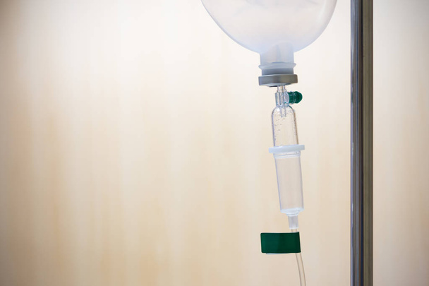 Крупним планом сольовий розчин крапельниці для пацієнта та інфузійного насоса в лікарні, з копіюванням простору дерев'яних стін фону на розкішній VIP-кімнаті
. - Фото, зображення