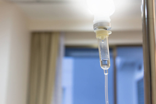 Close up saline solution drip for patient and infusion pump in hospital, with copy space window at luxury VIP room, effect light. - 写真・画像
