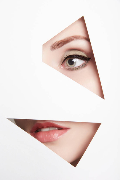 young woman behind paper.eye and lips.female face parts - Photo, image