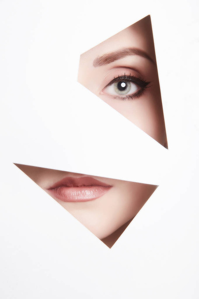 beauty young woman behind paper.eye and lips.female face parts - Foto, imagen
