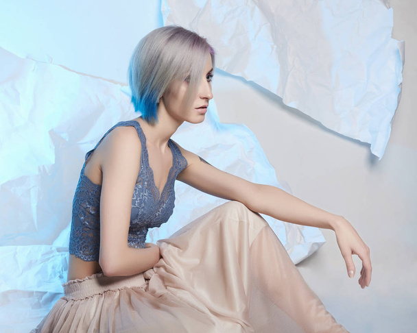 blue color hair beautiful woman.sensual blond girl with haistyle and make-up sitting over paper background - Zdjęcie, obraz