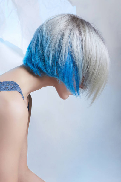 blue color hair woman.sensual blond girl sitting over paper background - Fotó, kép