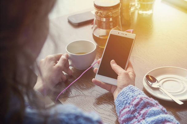 woman using smartphone in coffee shop in cafe with cup of coffee - Foto, Imagem
