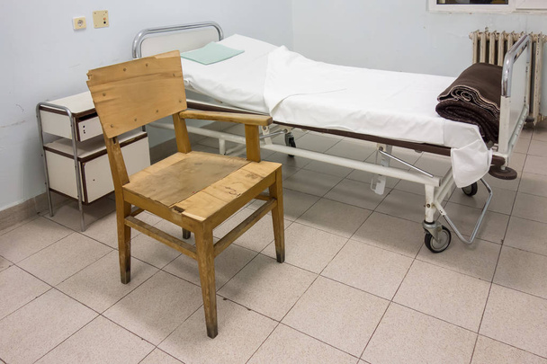 Interior do quarto do hospital com cama e cadeira velha
 - Foto, Imagem