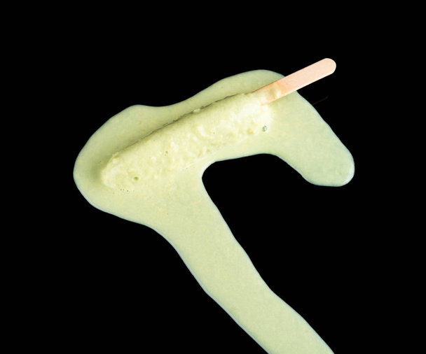 zöld popsicle egy olvadó folyamat, a fekete háttér - Fotó, kép