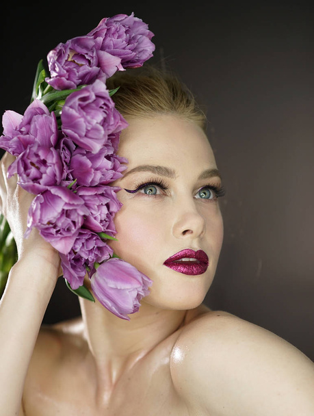 Mooi meisje met paarse tulpen Flowers.Beauty Model vrouw gezicht. Perfecte huid. Professionele Make-up.Makeup. Mode kunst - Foto, afbeelding