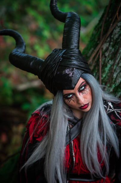 terrible woman with horns and amazing makeup in the forest - Fotoğraf, Görsel