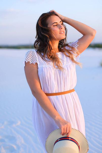 Menina bonita de pé na areia branca, vestindo vestido e mantendo
 - Foto, Imagem