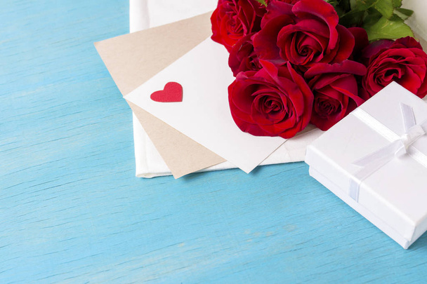 Bouquet of red roses White gift box clean sheet, blue wood background. Copy space. Romantic gift for Valentine's Day holiday. - Photo, Image