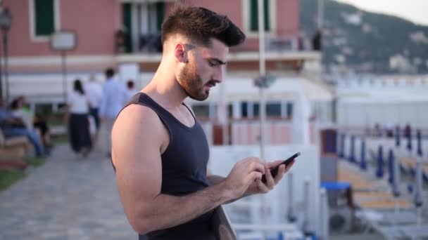 Man at the seaside using cell phone to type message - Video