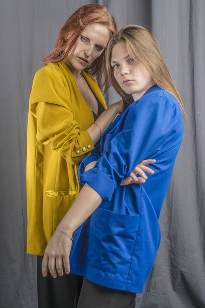Two cheerful girls in colorful jackets are dancing and having fun - Foto, Bild