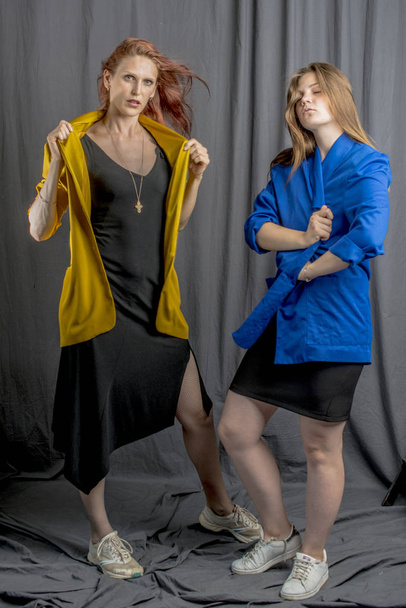 Two cheerful girls in colorful jackets are dancing and having fun - Foto, Imagem