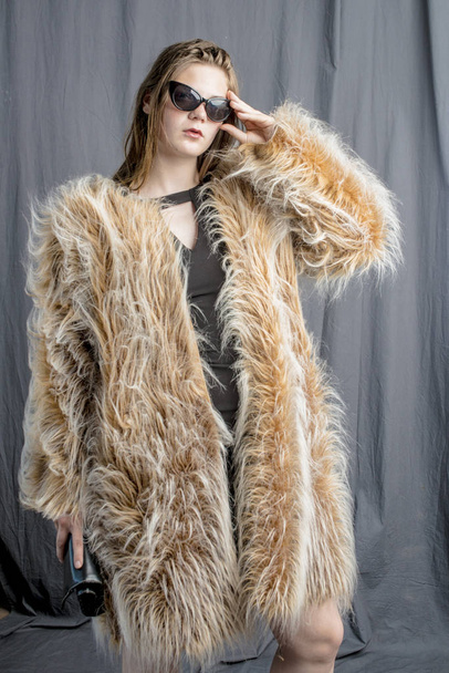 A young girl in a fur coat with a cloak with a handbag and an evening dress glamorous - Fotó, kép
