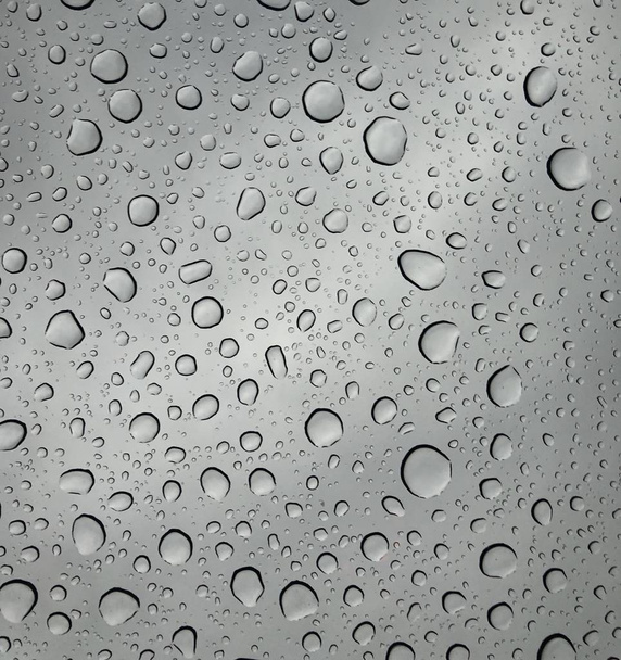 gouttes de pluie sur la surface des lunettes de fenêtre avec un fond nuageux Modèle naturel de gouttes de pluie isolées sur un fond nuageux
  - Photo, image