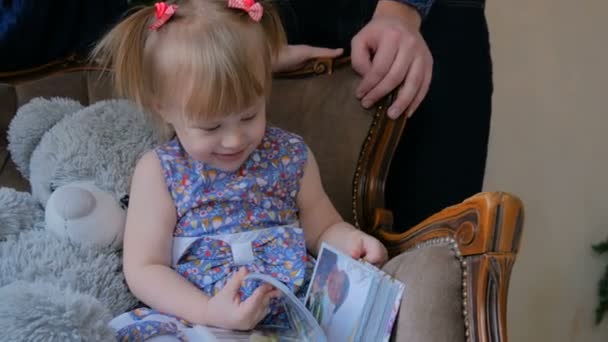 Mała dziewczynka patrząc fotoksiążki w domu. - Materiał filmowy, wideo