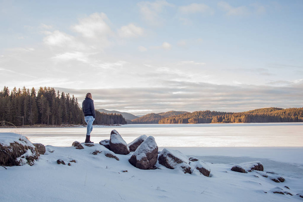 若い美しい女性が冬の湖に近いポーズ - 写真・画像