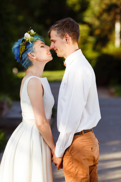 Young wedding couple enjoying romantic moments outside on a summer meadow. The girl has blue hair. - Fotó, kép
