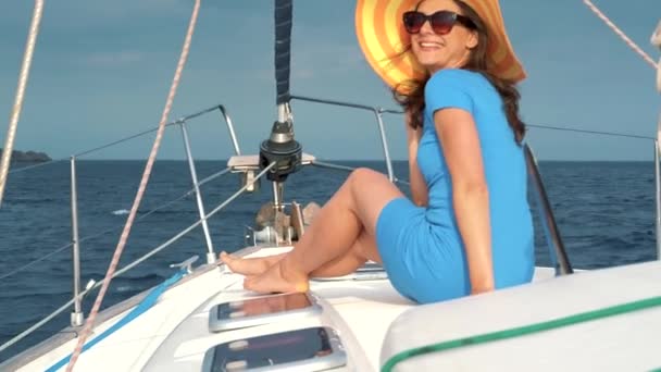 Kobieta w żółtym kapeluszu i niebieska sukienka dziewczyna opiera się na pokładzie jachtu na sezon letni w ocean. Zwolnionym tempie - Materiał filmowy, wideo