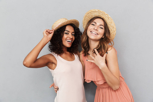 Portrait of two happy young women dressed in summer clothes looking at camera isolated over gray background - Foto, imagen