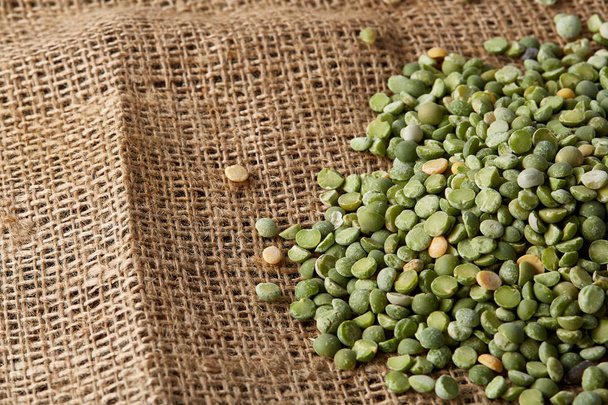 Pile of green peas on burlap tablecloth, close-up, top view, selective focus. - Fotoğraf, Görsel
