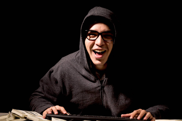 Hacker em um capuz roubando informações com computador no fundo escuro
 - Foto, Imagem