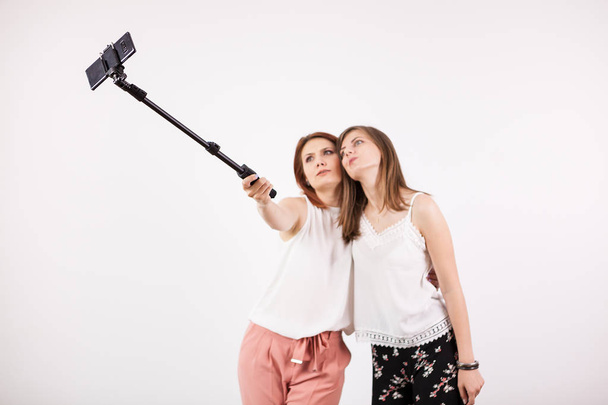 Dos hermosas jóvenes tomando una selfie con un palo de selfie
 - Foto, imagen