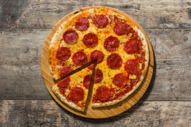 Pizza de pepperoni italiano caliente sobre mesa de madera. Vista superior
 - Foto, imagen