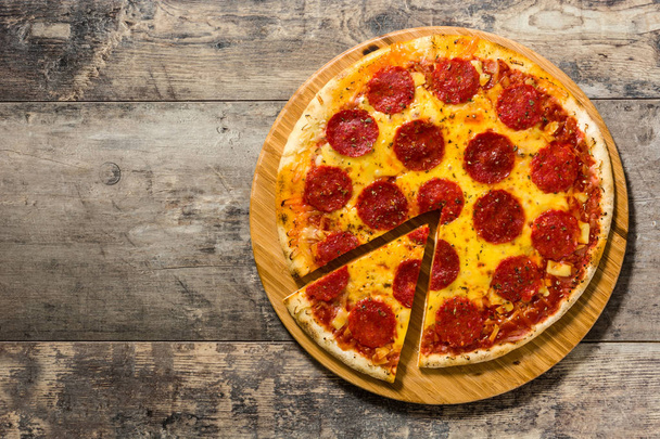 Hot Ιταλικά πεπερόνι πίτσα στο ξύλινο τραπέζι. Το Top view. Copyspace - Φωτογραφία, εικόνα