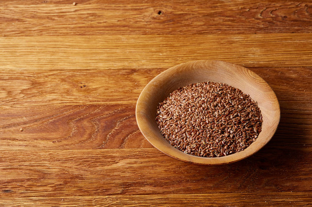 Close-up buckwheat in a round wooden plate over homespun tablecloth, top view, selective focus. - Fotó, kép