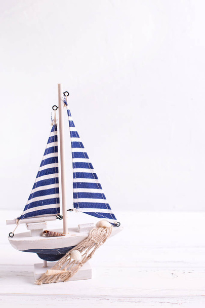 Decorative  wooden toy boat  on white  textured background.  Place for text.  Summer, vacation concept. Vertical image. - Fotografie, Obrázek