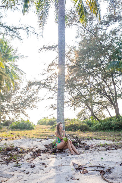 Summer lifestyle young with coconut girl standing near palms. Wearing tropical swimsuit. Phuket, Thailand - 写真・画像