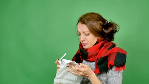Portrait of an attractive brunette with flu. The girl has a cold, fever, neck is wrapped in a scarf. She sprays a throat with a spray for her throat. Angina, influenza, scarlet fever, virus - Footage, Video