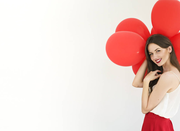 白い背景の赤い風船と魅力的な若い女性 - 写真・画像