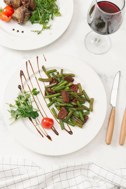 Roasted green beans served with sun-dried tomatoes and sauce on white plate - Photo, Image