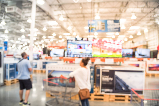 Bulanık müşteri Elektronik Bölümü'nde, televizyon perakende mağazalar alışveriş. ABD'de toptan mağaza rafındaki TV görüntüler. Ufuk ambar iç teknoloji koridor, raflar, bokeh arka plan - Fotoğraf, Görsel