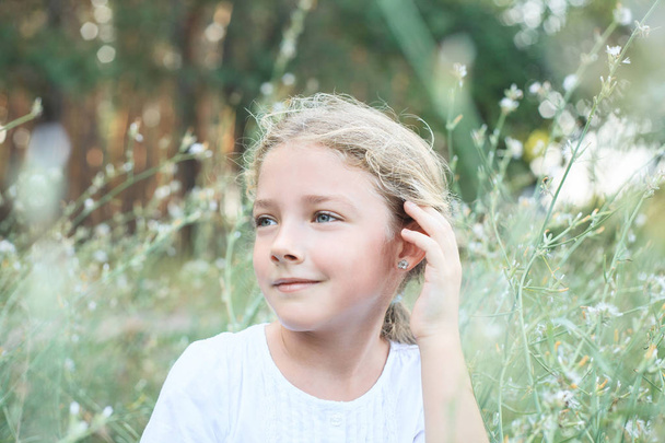 Portrait of a cute little girl on the nature in flowers while walking. - Photo, Image