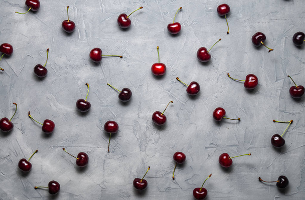 Flat background: Fresh ripe red Cherry is evenly spread out on a gray background. - Fotografie, Obrázek