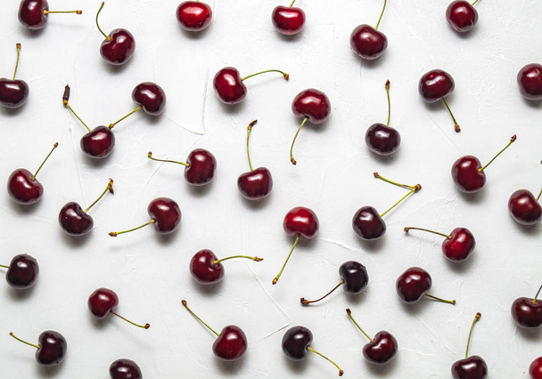 Flat background: Fresh ripe red Cherry is evenly spread out on a white background. Flatlay. - Photo, image