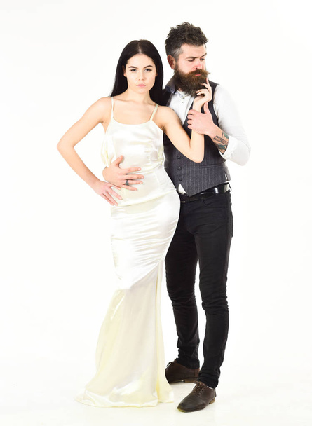 Wedding concept. Couple in love, bride and groom in elegant clothes, white background. Bearded hipster with attractive bride dressed up for wedding ceremony. Woman in wedding dress and man in vest. - Valokuva, kuva