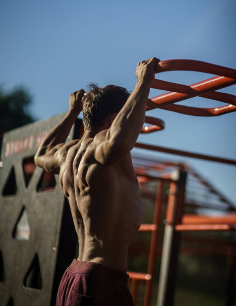 Muscular man during his workout on the street with horizontal bar. - Фото, зображення