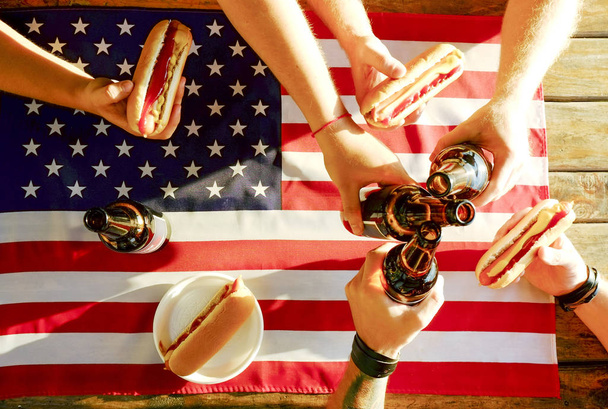 4. července moje oslava, mladíci ruce drží láhev piva, dovolená label design, den Happy nezávislosti, hot dog, hořčice, dohonění. Americká vlajka, řeka rekreační oblast. Zblízka, pozadí - Fotografie, Obrázek