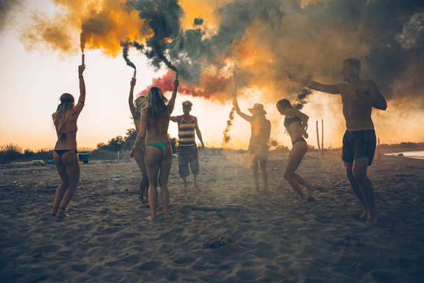 Group of friends making party on the beach at sunset time - Foto, afbeelding