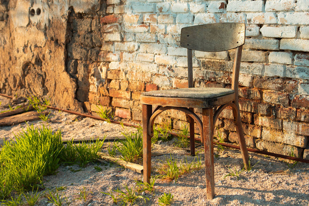 vanha puinen tuoli seisoo lähellä seinää raunioitunut talo
 - Valokuva, kuva