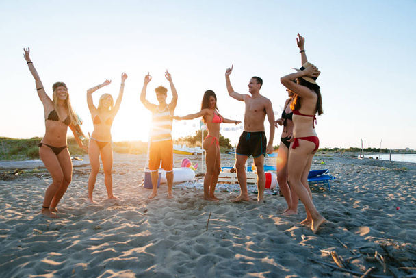 Group of friends making party on the beach at sunset time - 写真・画像